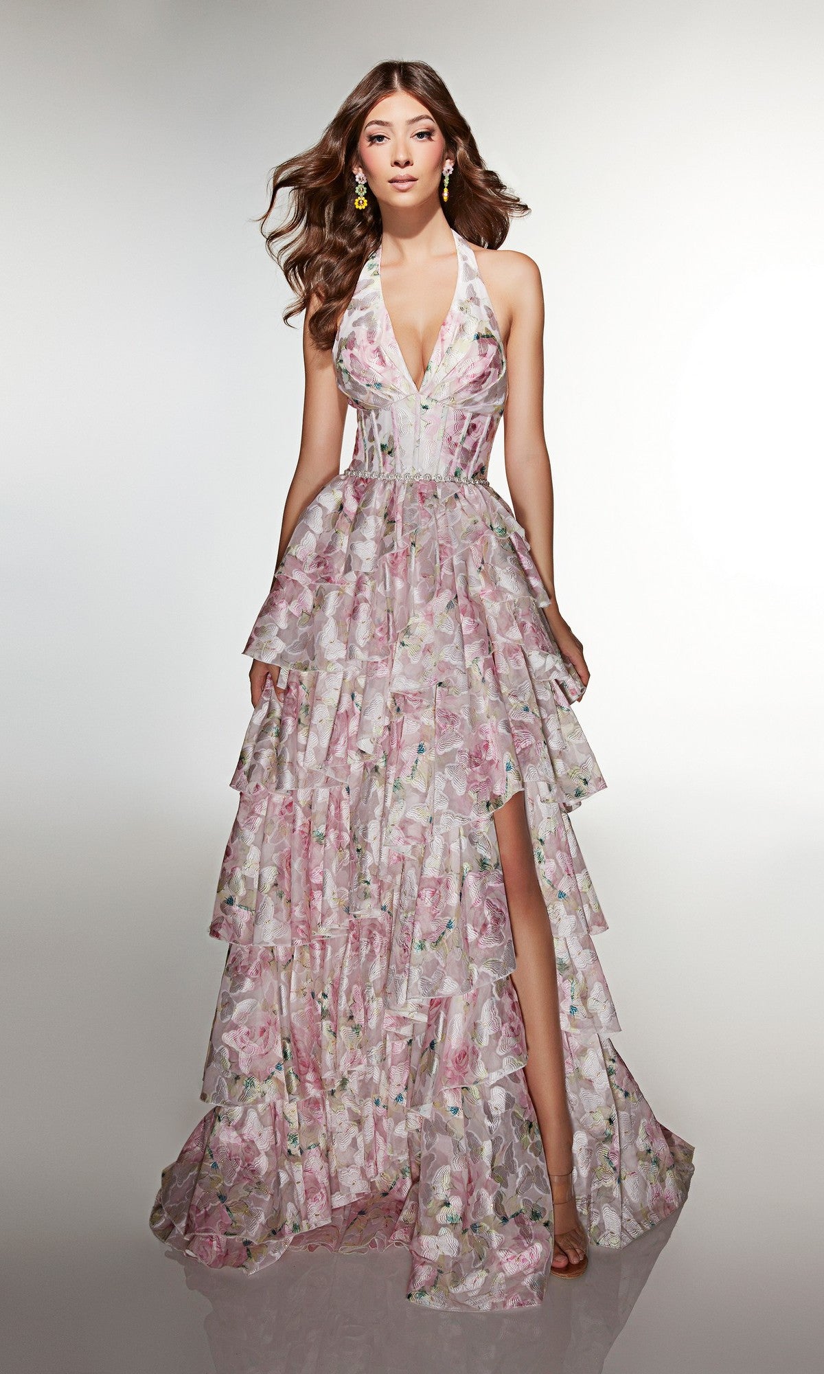 Woman wearing the Alyce 61996 long prom dress featuring a sleeveless, layered floral organza design with a deep V-neckline and high slit, posing against a plain light background.